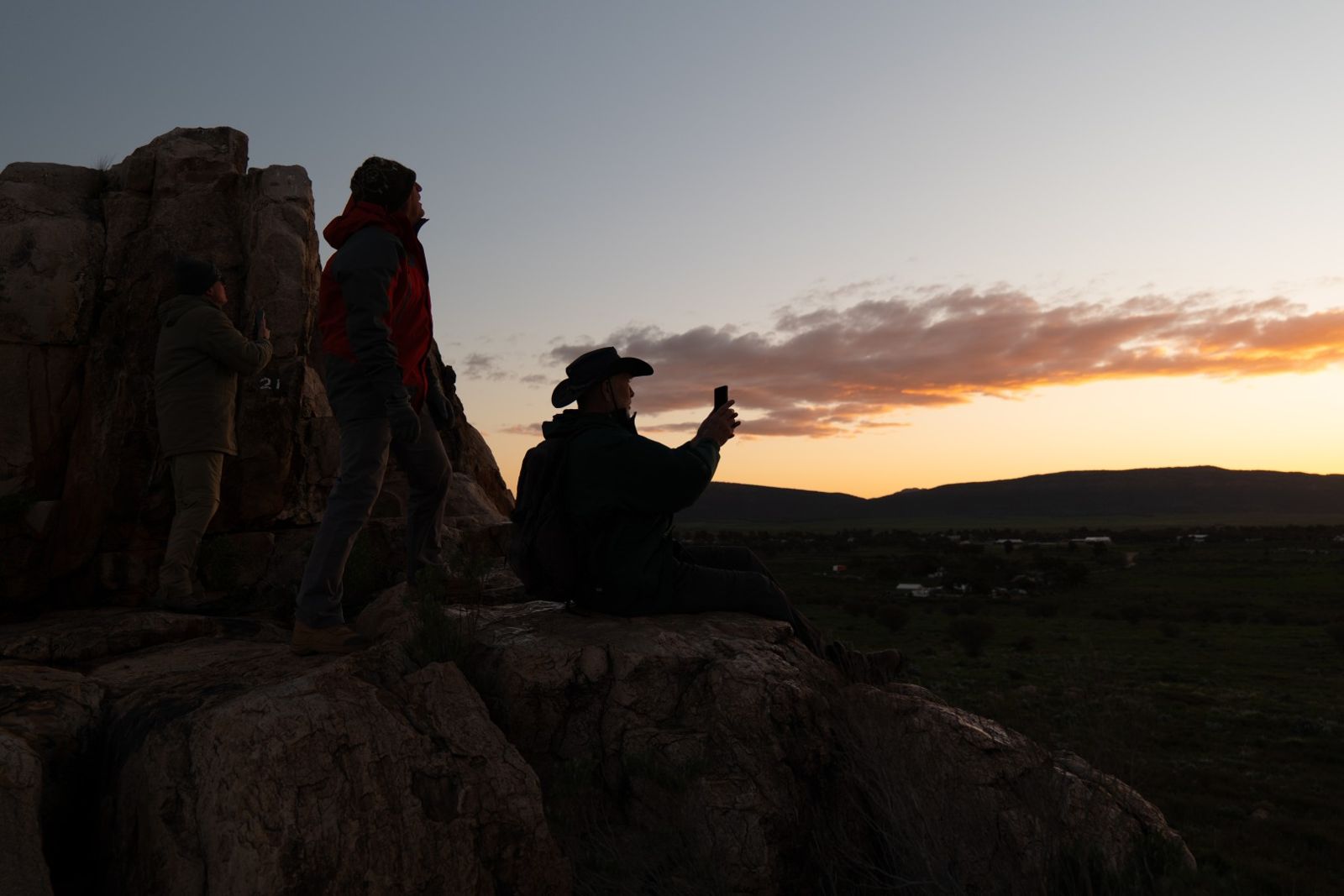 Three members of the team silhouetted on rocks at sunset, Castle Rock Lookout near Hawker