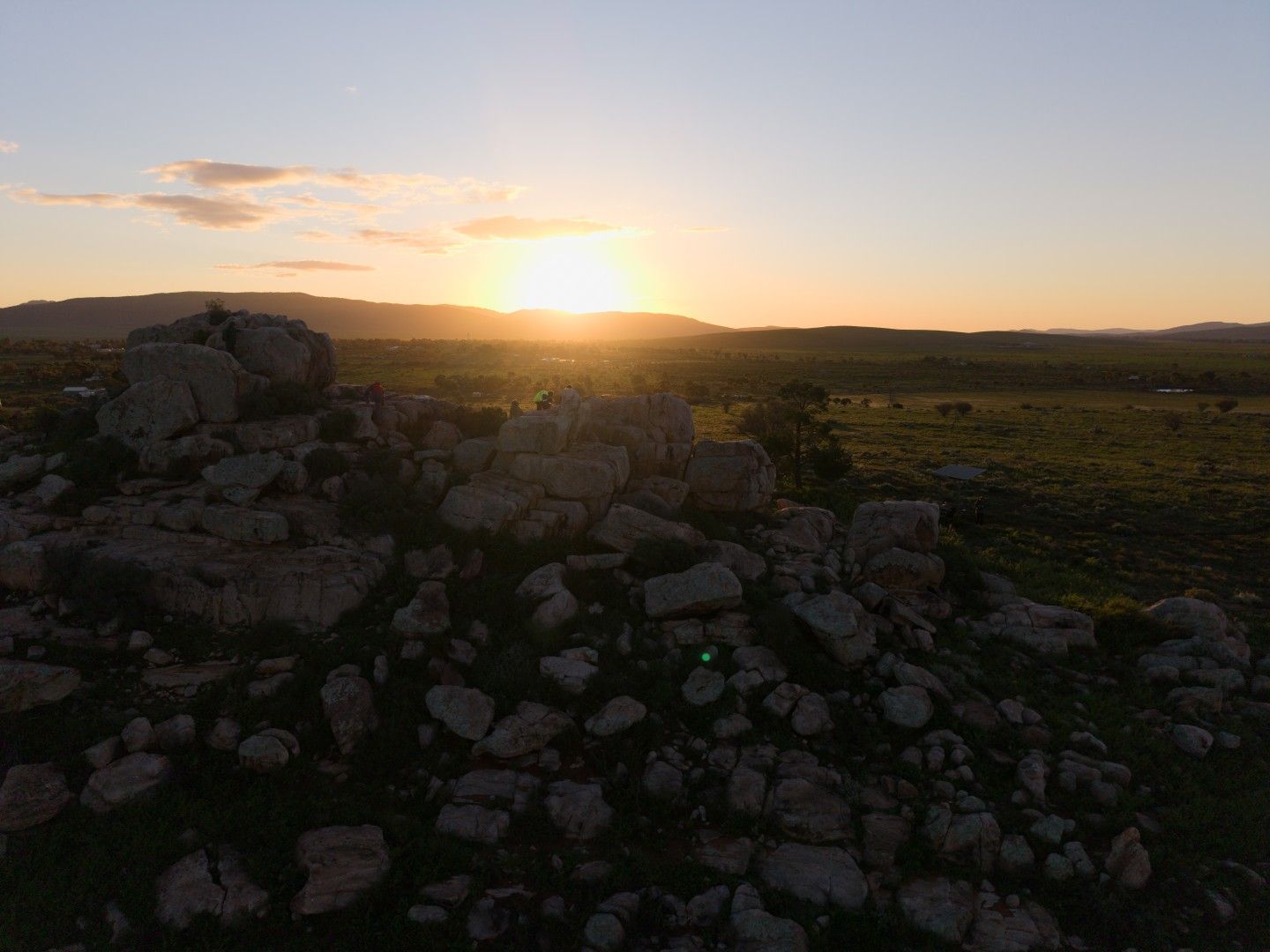 The sun setting over a rocky outcrop and flat plains, seen from above