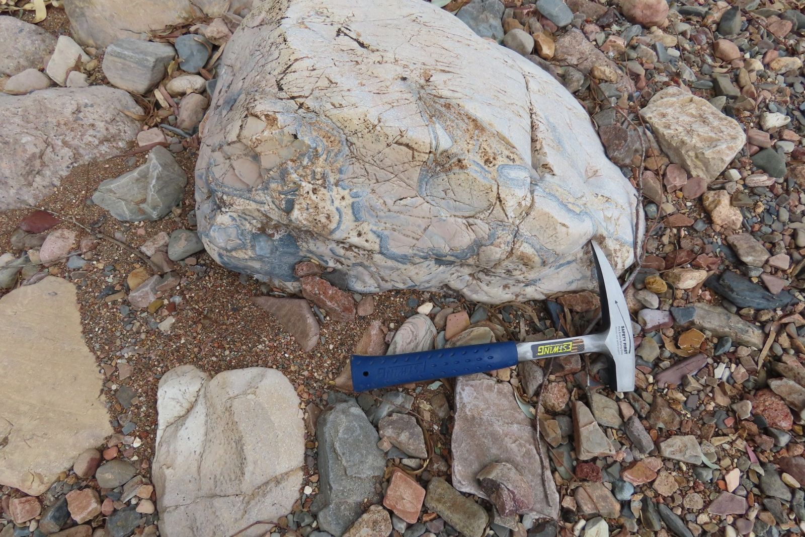 A pale boulder with swirling patterns beside a hammer