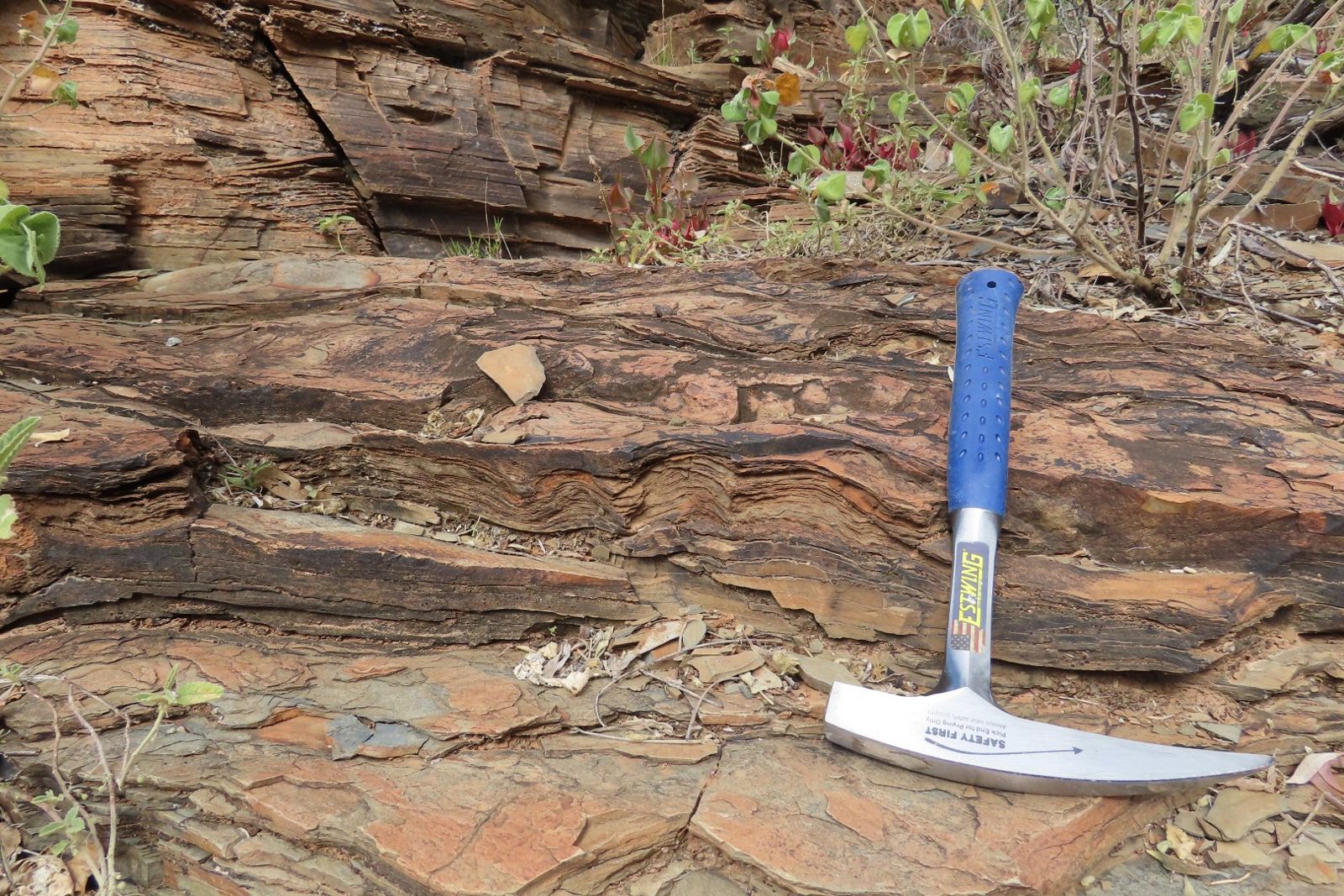 Wavy layered rock with a geology hammer