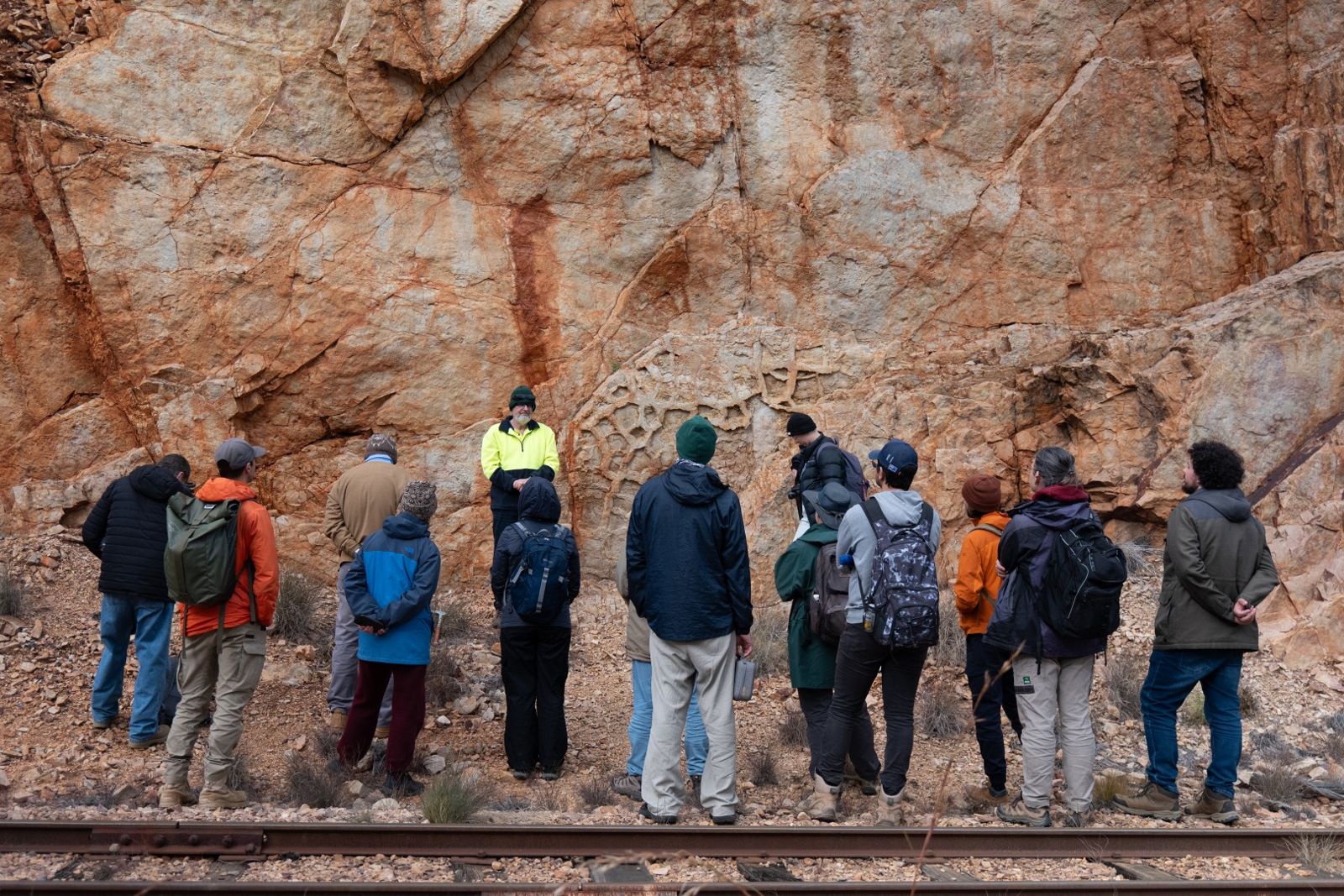 The group standing beside the railway line looking at a tall rock face
