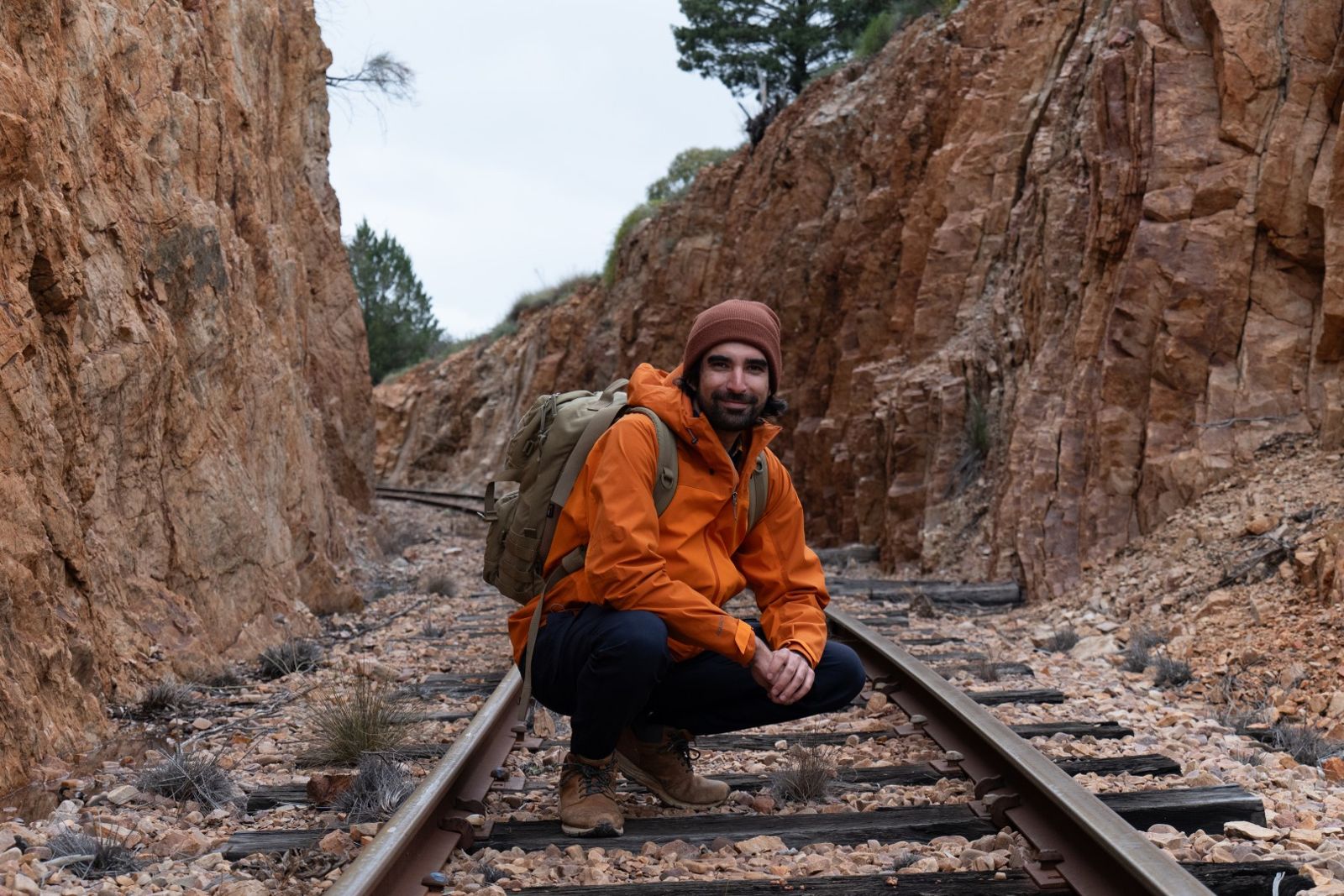 A team member crouching on the railway track between two rocky walls